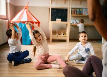 Group of kids exercising with their teacher at preschool.